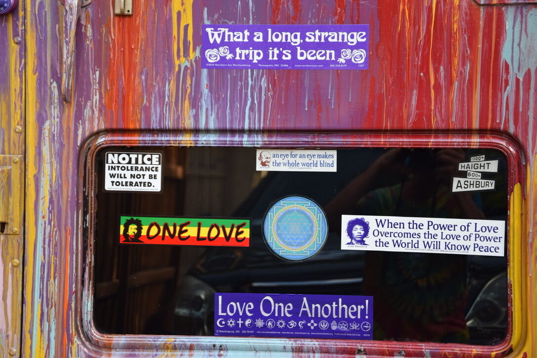 A collage of peace, love, and Grateful Dead-inspired bumper stickers on SUGAREE's back door glass