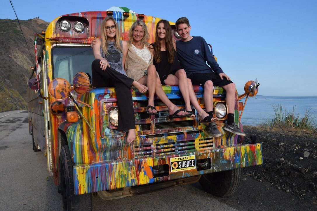 Cassidy, Kelly, Avery, and Dylan sitting on SUGAREE's hood along Highway 1 in California