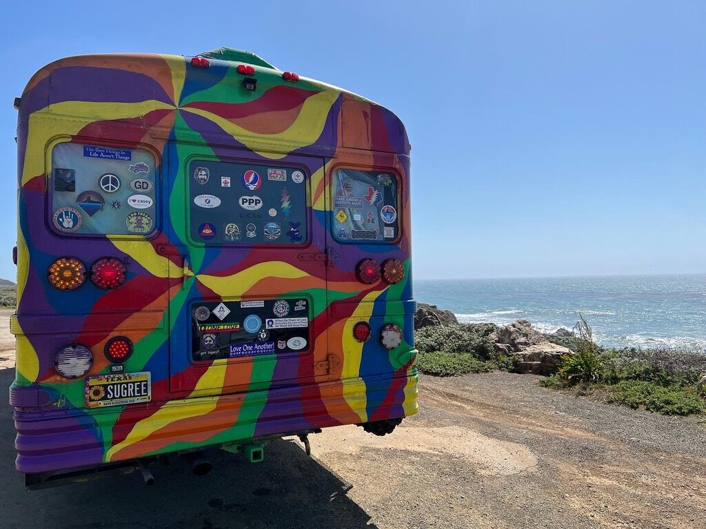 The rear of SUGAREE covered in bumper stickers, parked at a Pacific coastline overlook
