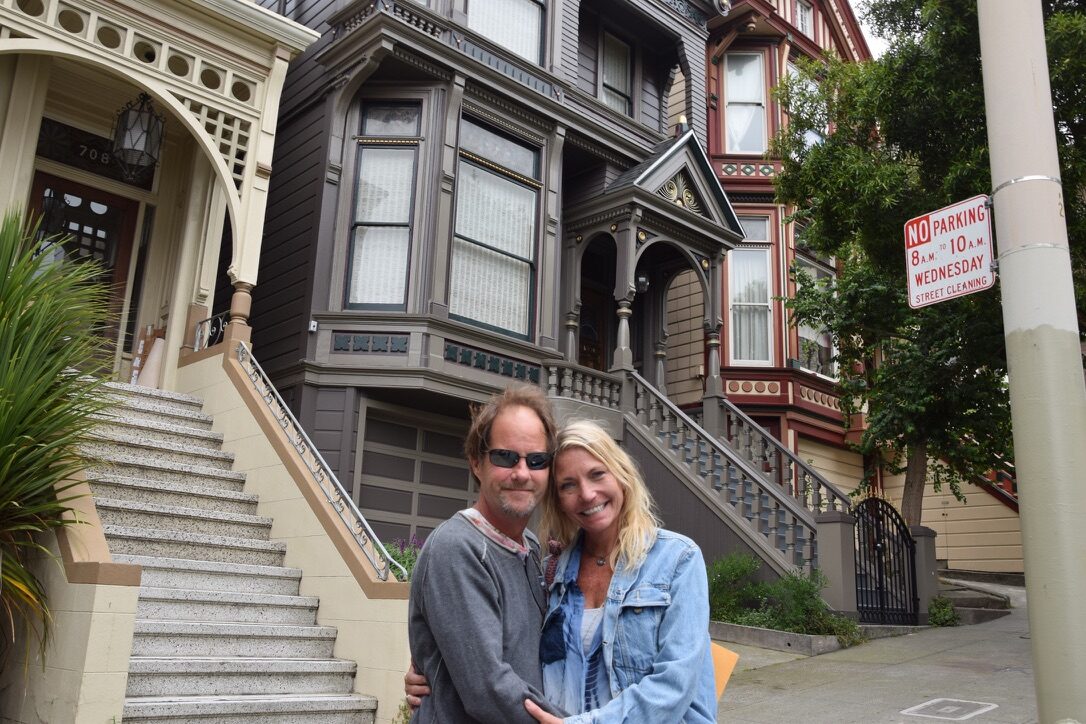 A couple embracing in front of a dark Victorian house in Haight-Ashbury