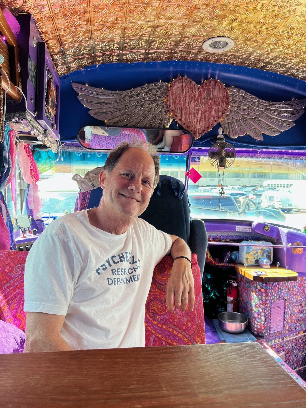 David seated at the wooden table up front, beneath the silver winged heart mounted over the windshield