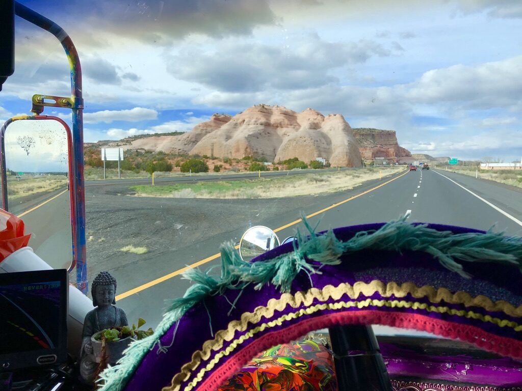 View through SUGAREE's windshield of a red rock formation along the highway