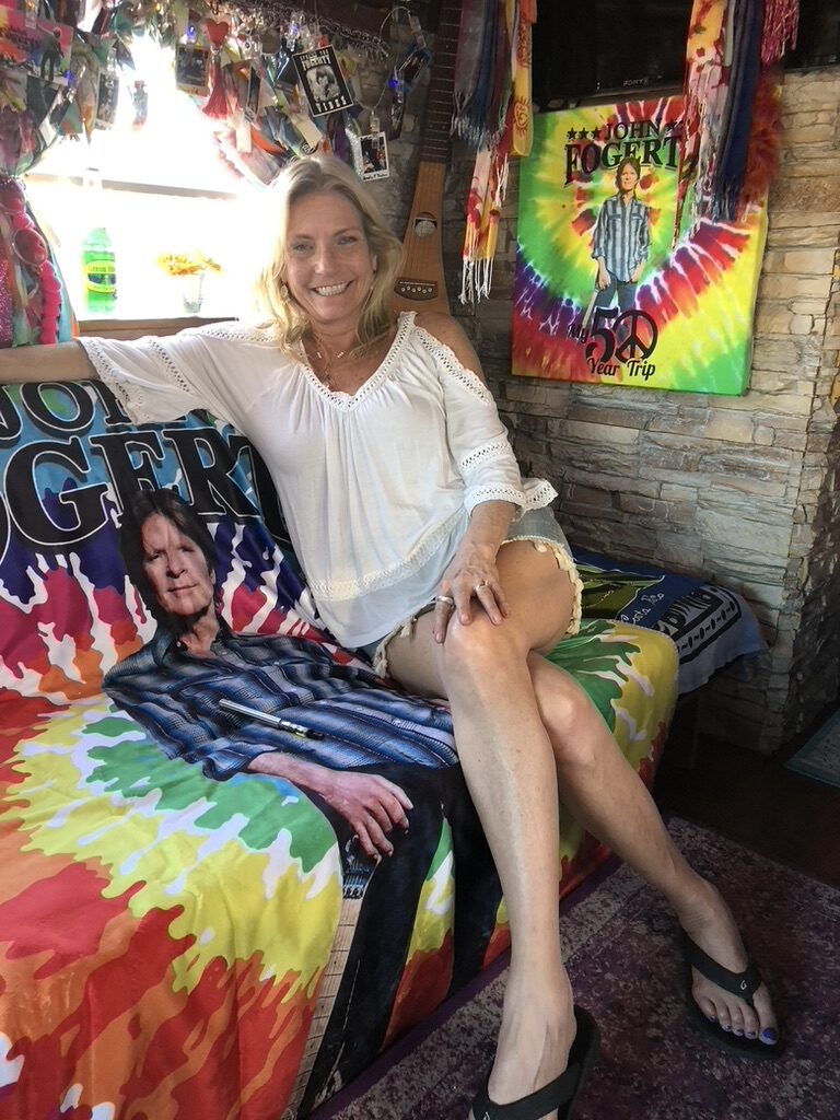 A woman sitting next to SUGAREE's John Fogerty tribute display inside the bus