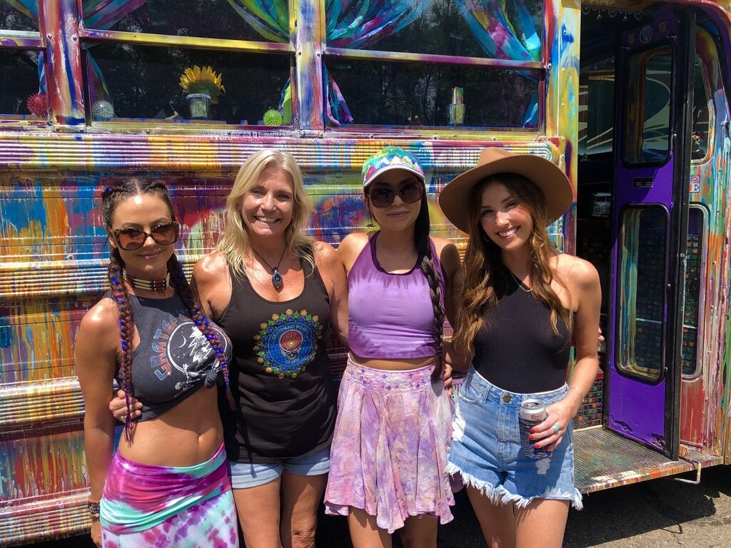 Four women posing in front of SUGAREE's colorful side