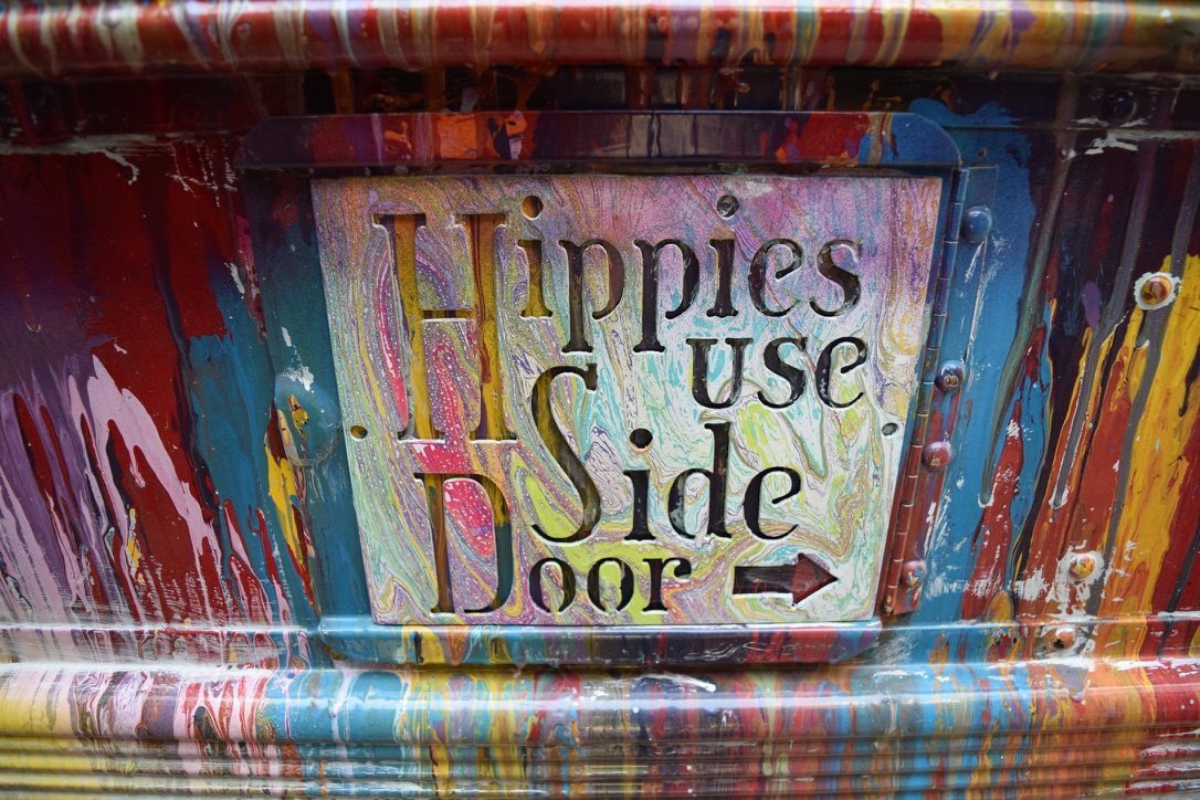 A hand-lettered 'Hippies Use Side Door' plaque set into SUGAREE's painted panels