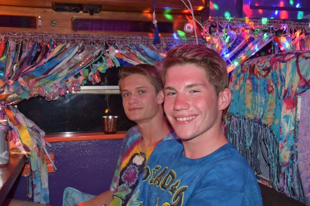 Two friends inside SUGAREE, string lights and tie-dye fringe overhead