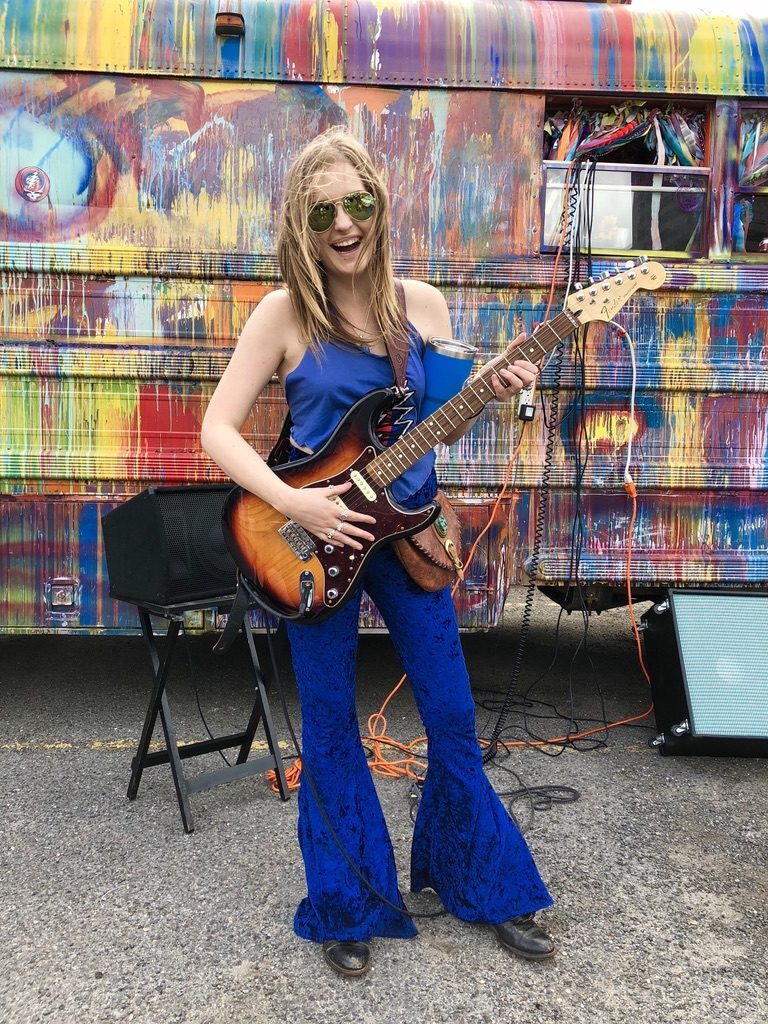 A friend playing electric guitar in front of SUGAREE's painted panels