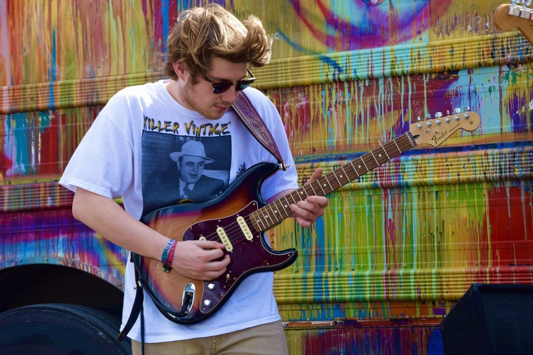 A guitarist playing in front of SUGAREE's painted side panels