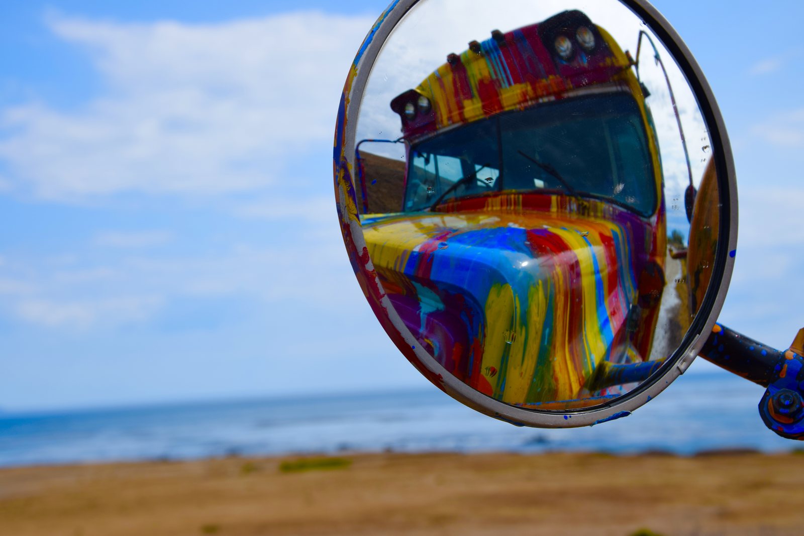 SUGAREE reflected in her round side mirror with the beach and ocean behind