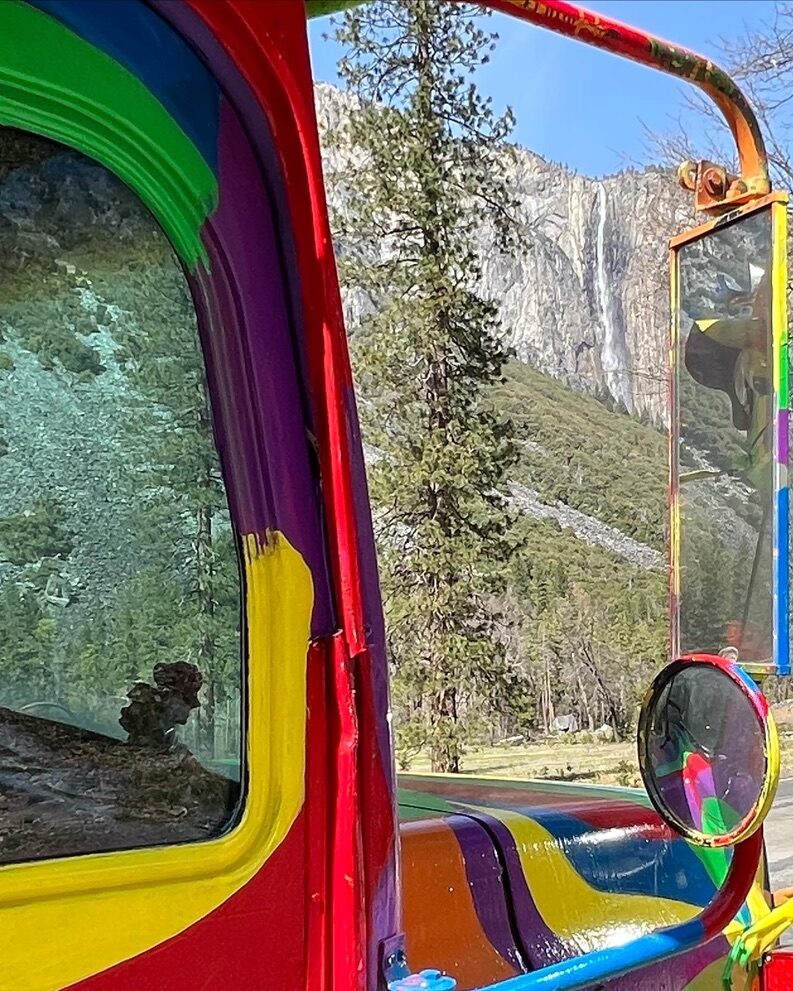 SUGAREE's painted side mirror reflecting a tall waterfall on a granite cliff
