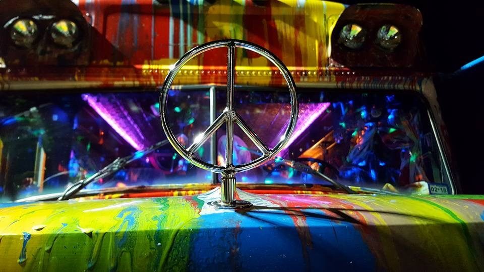 Close-up of the chrome peace sign hood ornament against SUGAREE's colorful paint