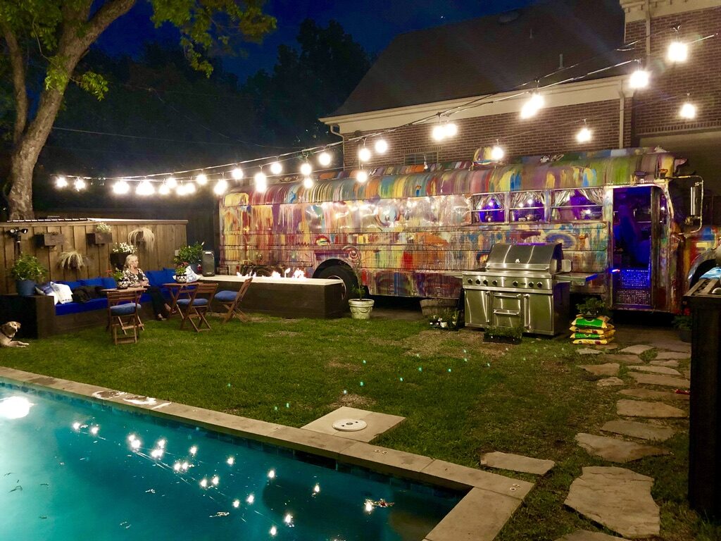 SUGAREE parked in a backyard by the pool, strung with lights at dusk