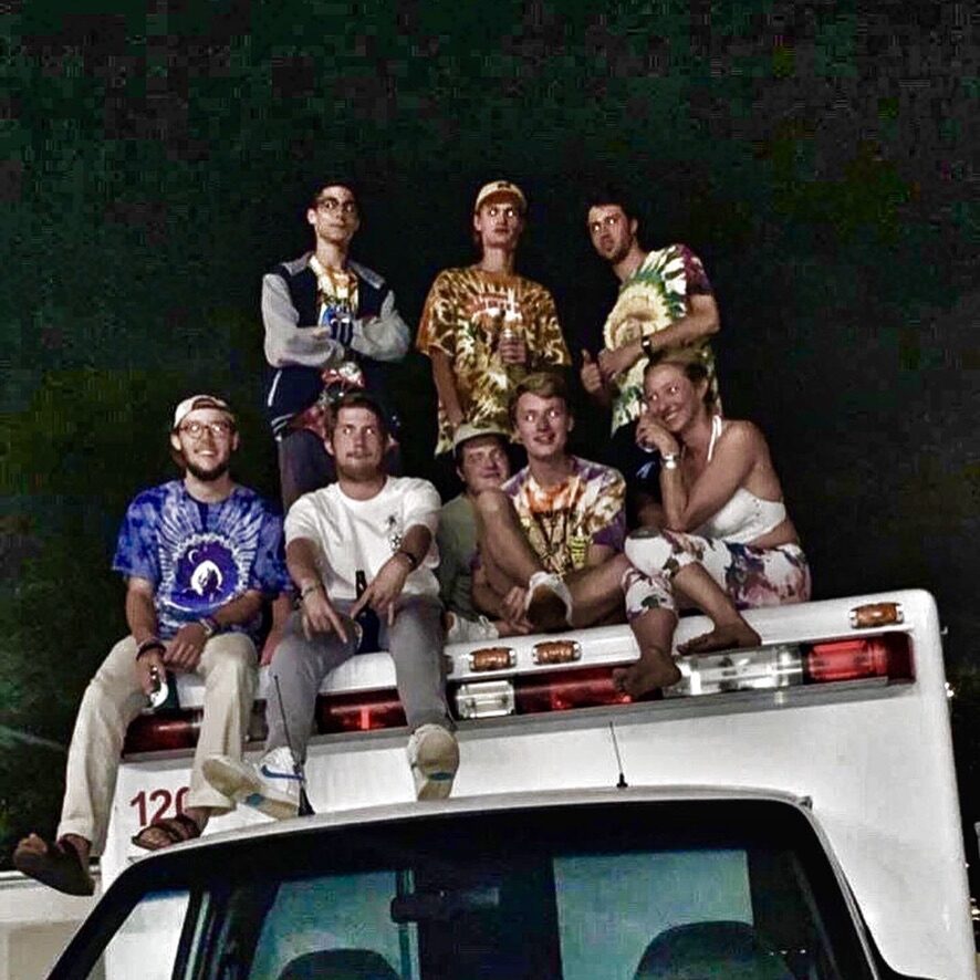 A group of friends sitting on top of a vehicle at night, celebrating