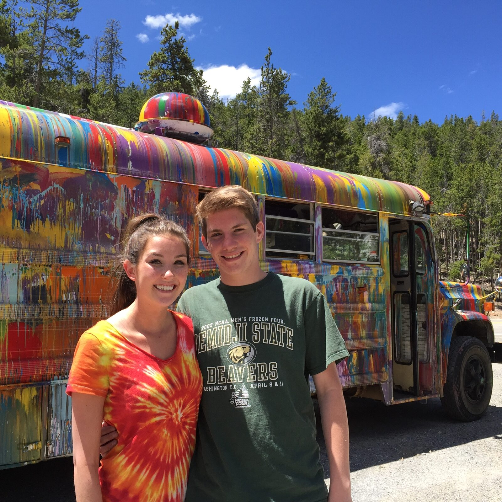 A brother and sister in front of SUGAREE on a forested mountain road