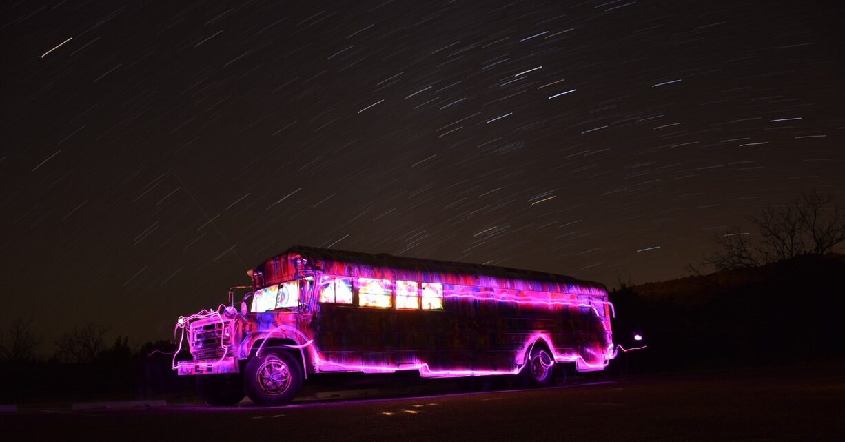 SUGAREE lit up in magenta light painting under a night sky full of star trails