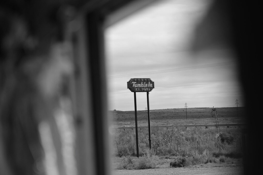 Black and white photo of the Tumble In RV Park sign, seen through SUGAREE's window