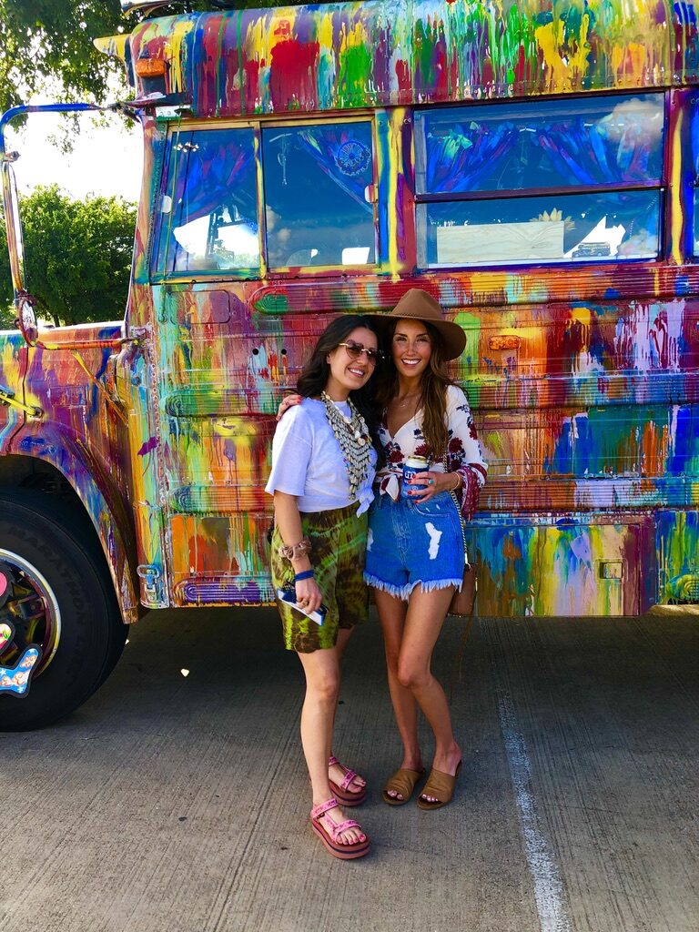 Two women posing in front of SUGAREE's colorful paint job at a festival