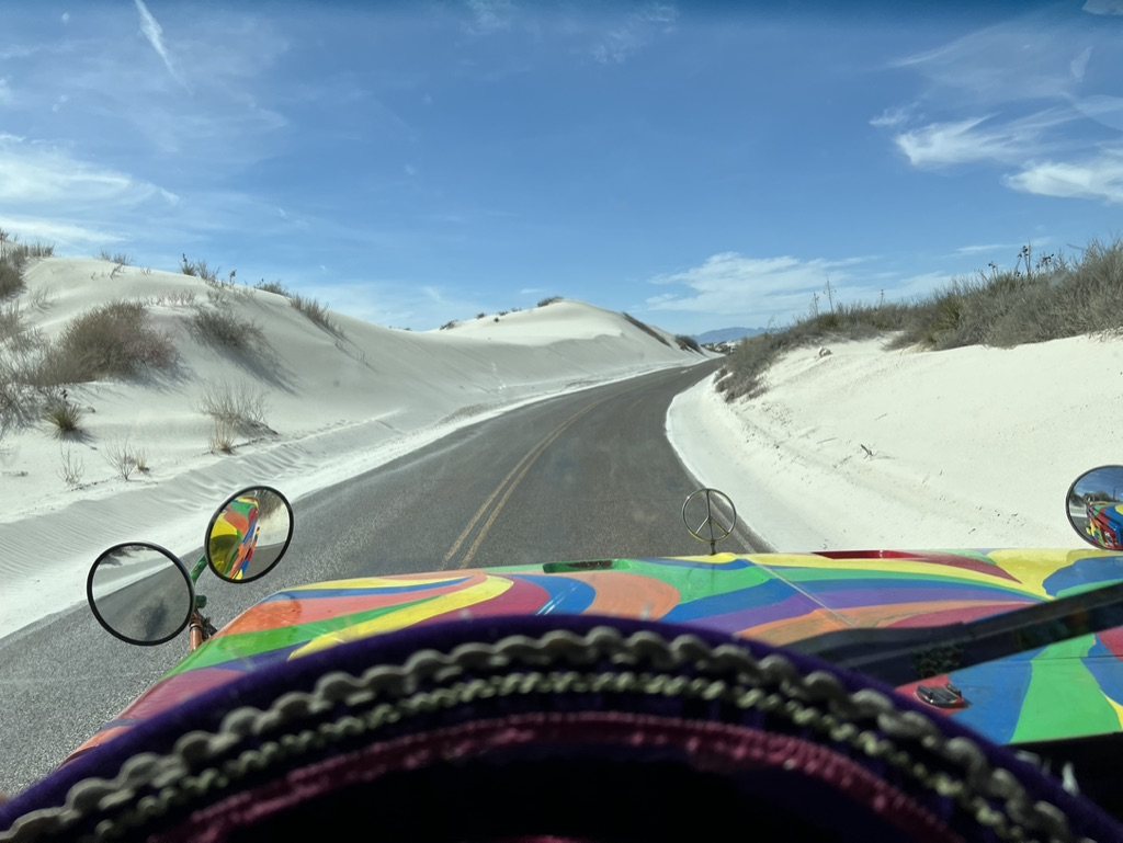 Windshield view of a road cutting through bright white sand dunes