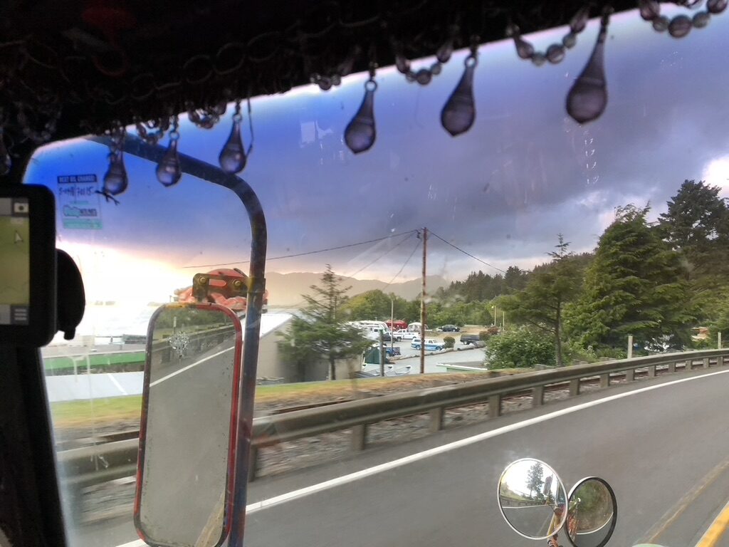 Windshield view along a coastal road past sand dunes
